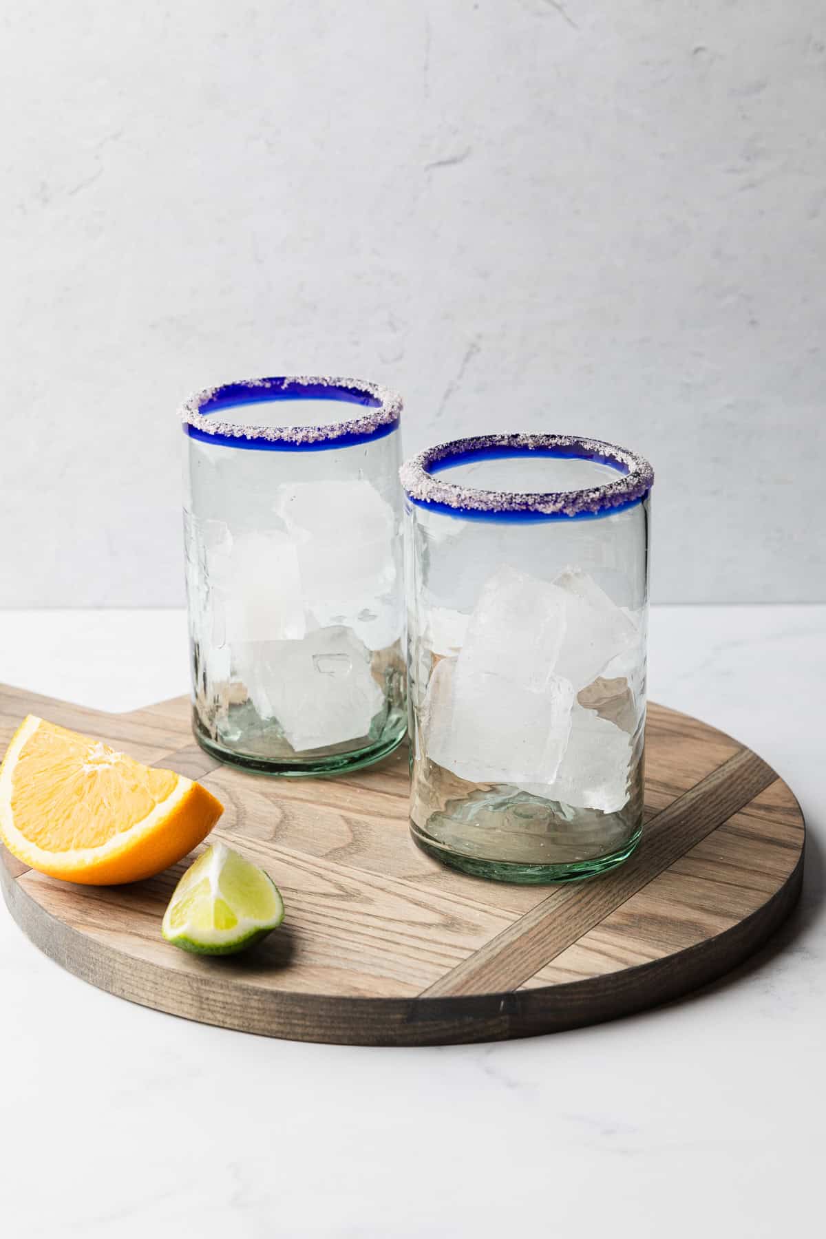 Two salted rim glasses with ice cubes.
