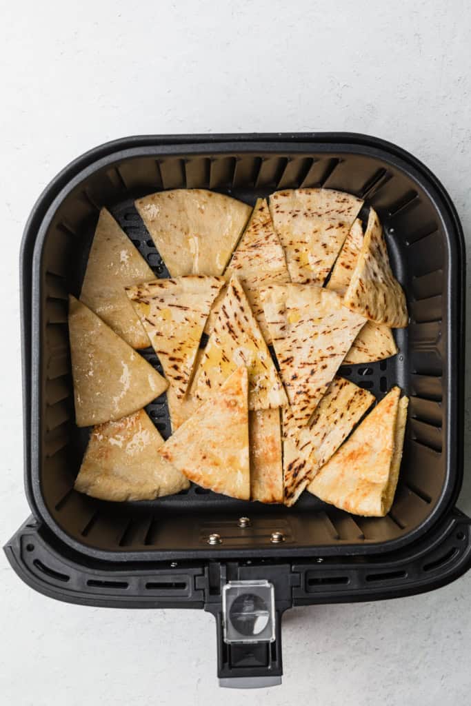 Pita bread cut into triangles in the air fryer basket.
