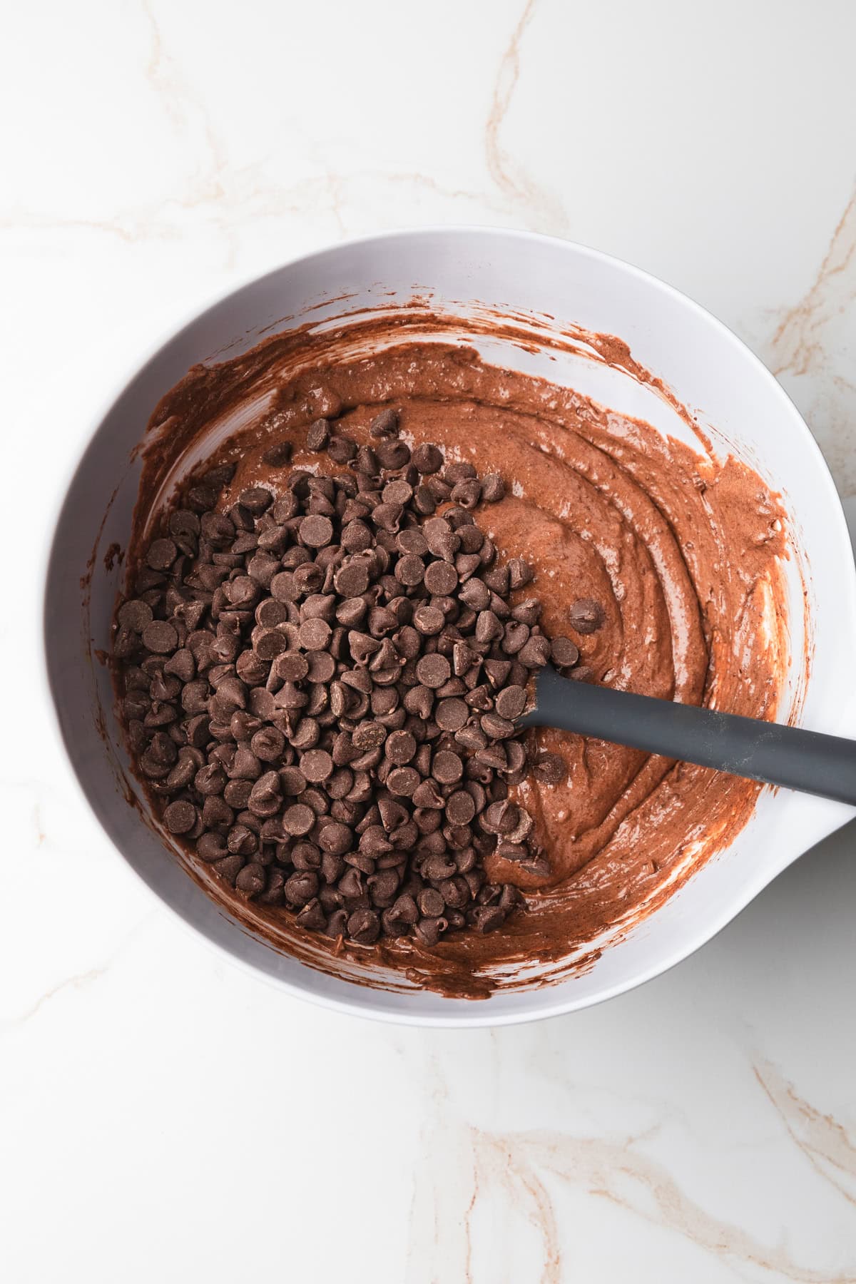 Adding chocolate chips to the cake batter.