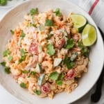 Mexican macaroni salad with ham in a bowl with some lime wedges.