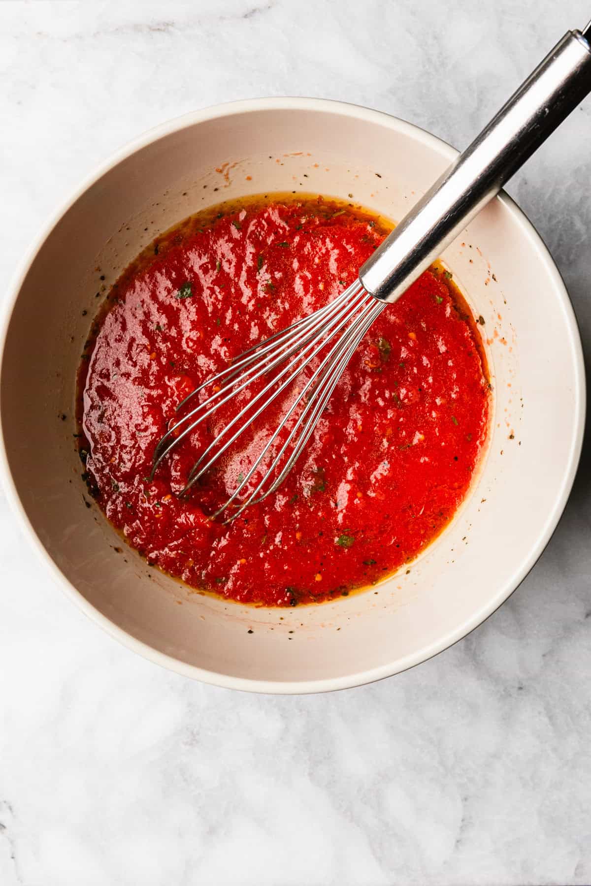 Mixing olive oil and other ingredients to make pizza sauce.