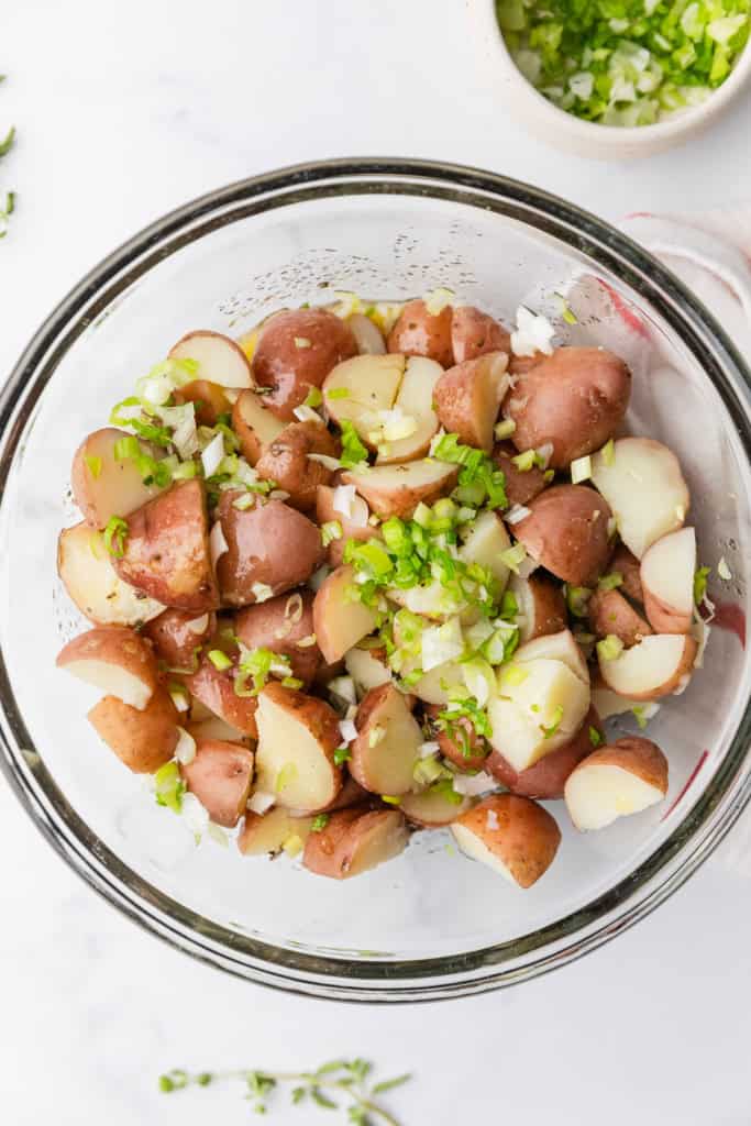Adding chopped green onions to make the greek potato salad.
