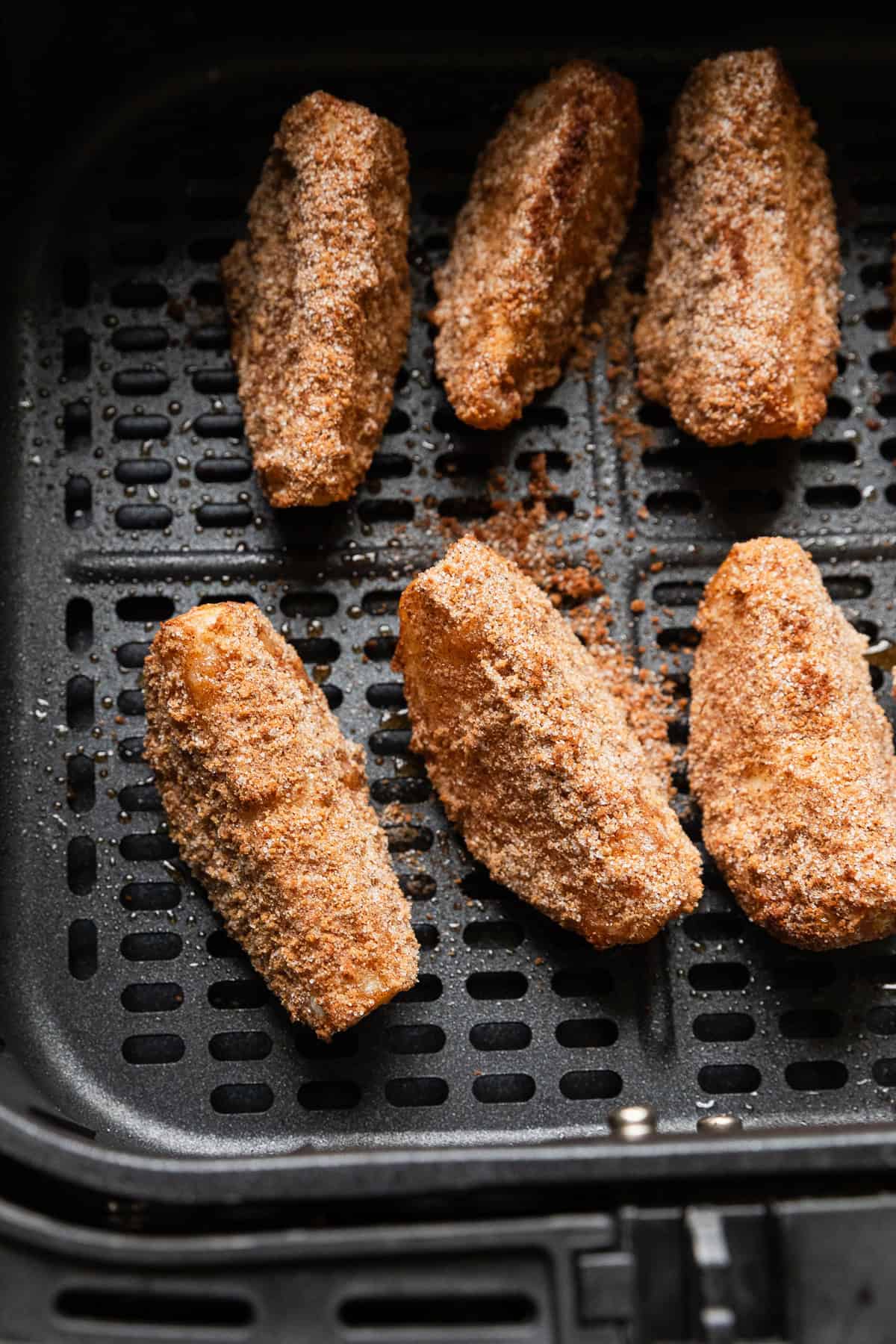 Apple slices cooked in an air fryer basket.