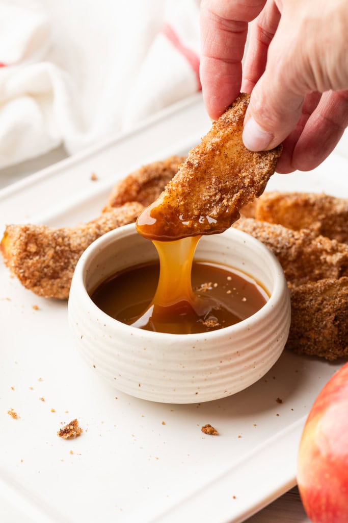 Dipping an apple slice in caramel sauce.