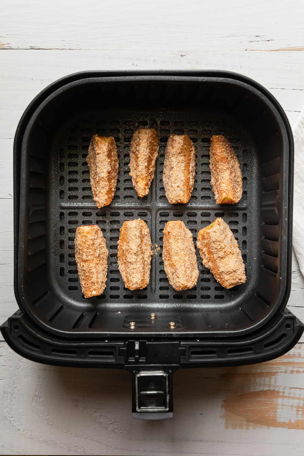 Apple slices in an air fryer basket.