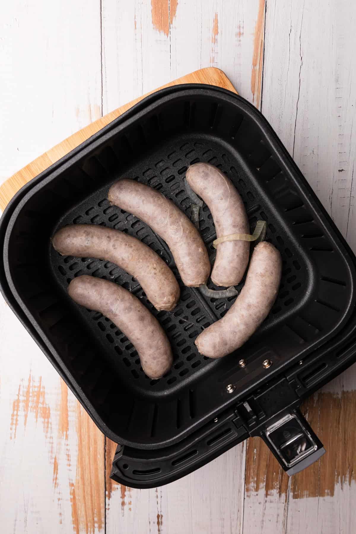 Brats in air fryer basket.