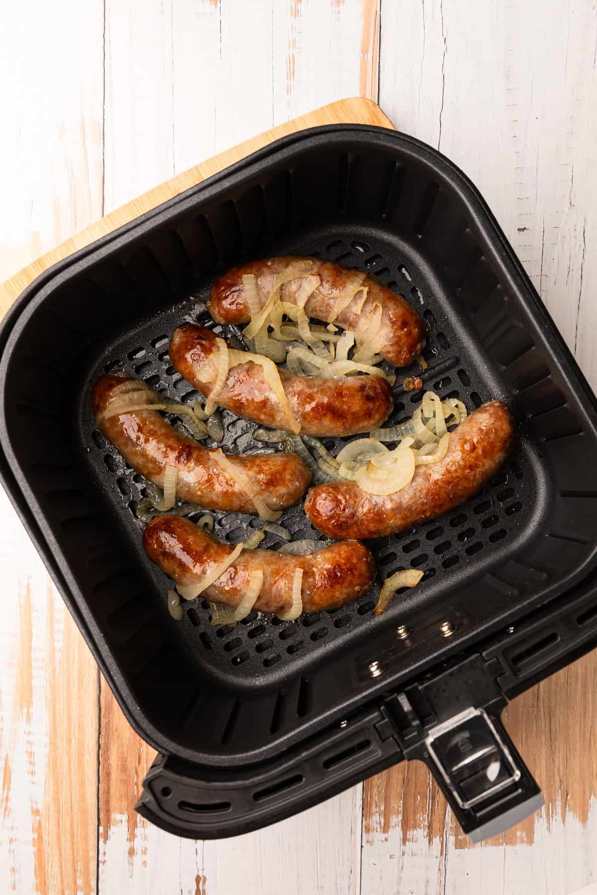 Golden brown brats in the air fryer basket.