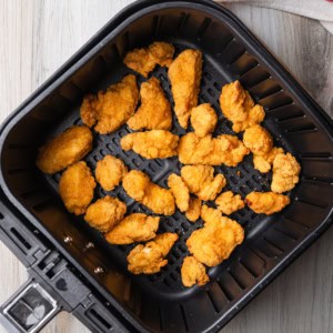 Popcorn chicken in an air fryer basket.