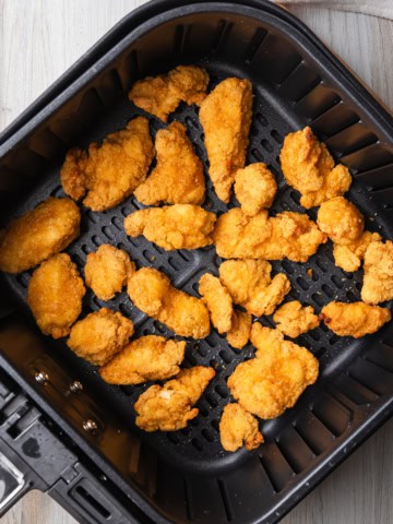 Popcorn chicken in an air fryer basket.