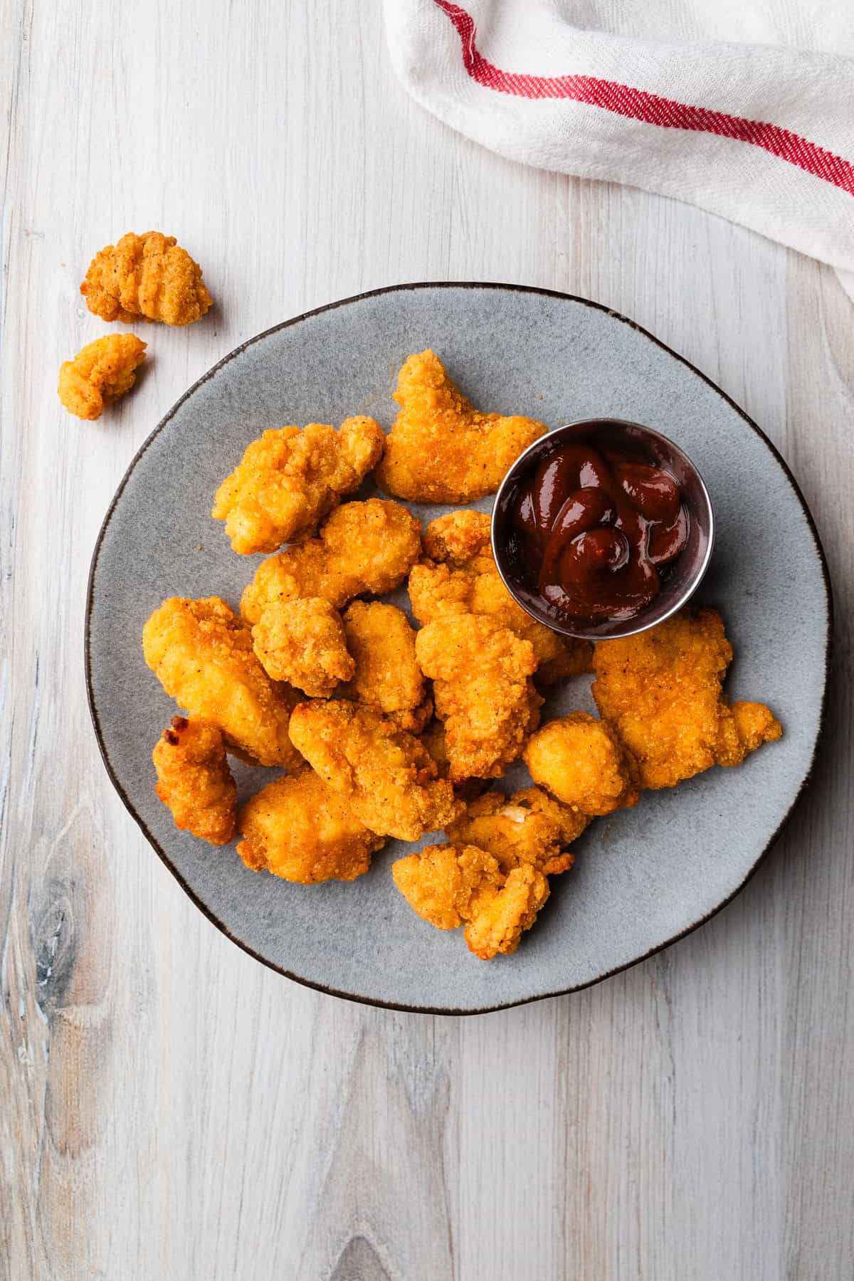 A plate of popcorn chicken with dipping suace.