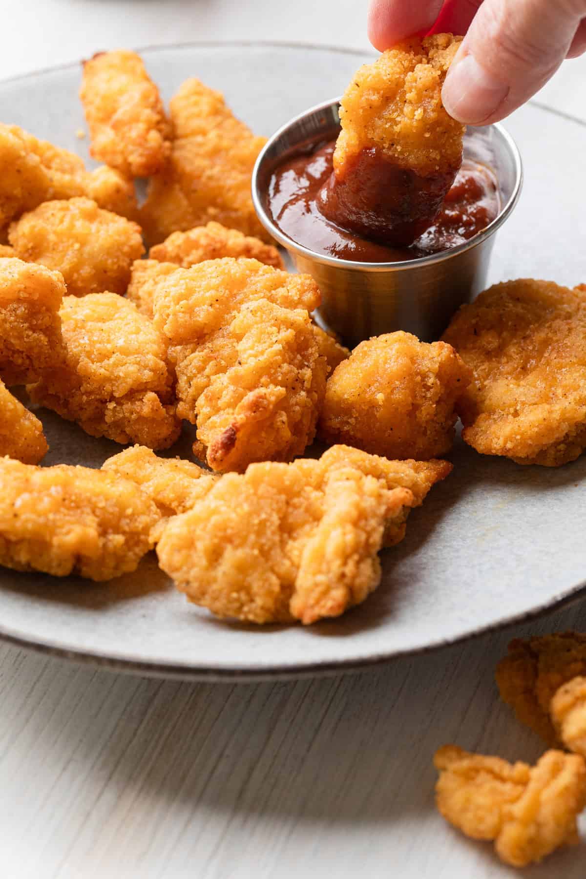 Popcorn chicken on a plate being eaten with dipping suace.