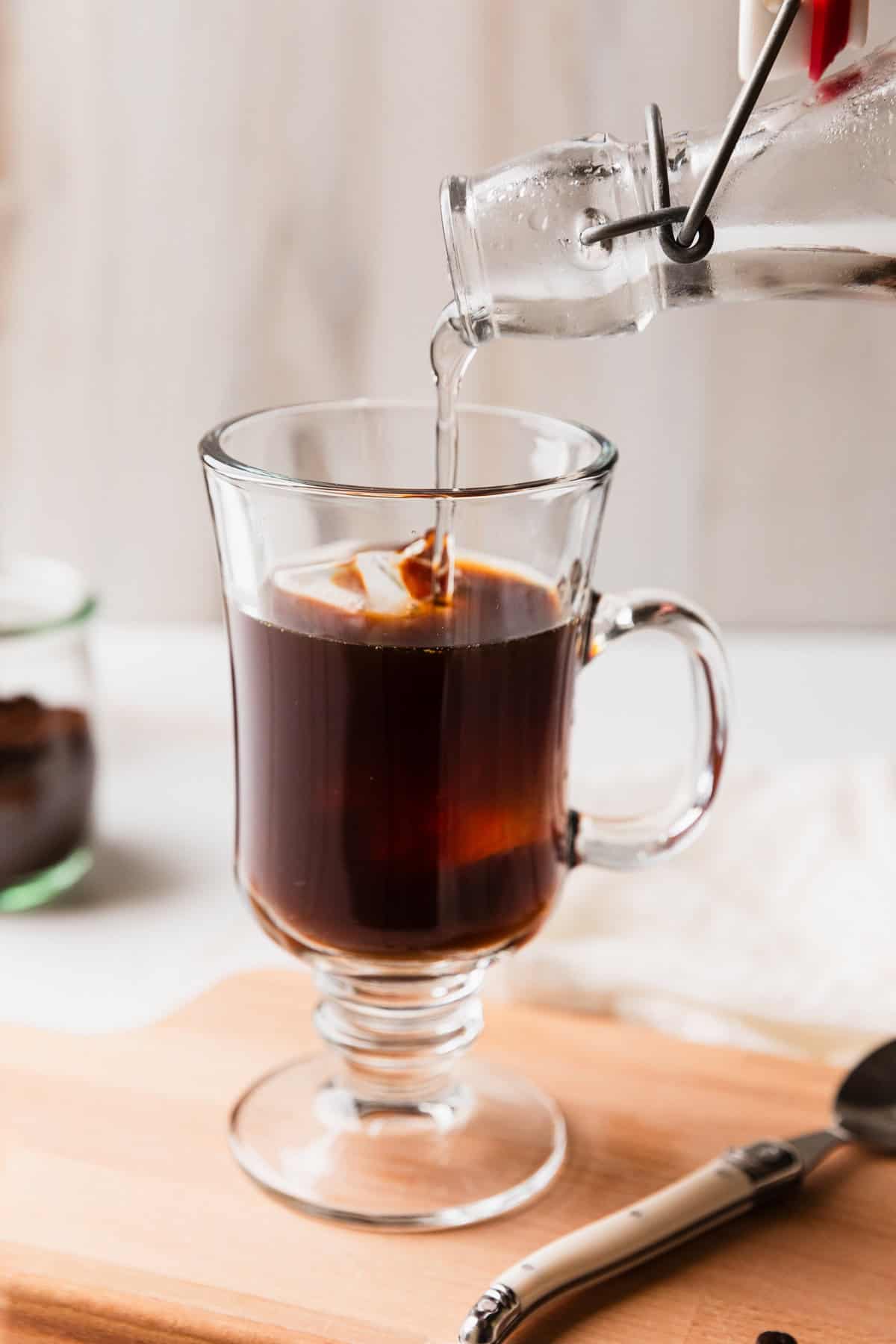 Pouring simple syrup in an iced coffee.