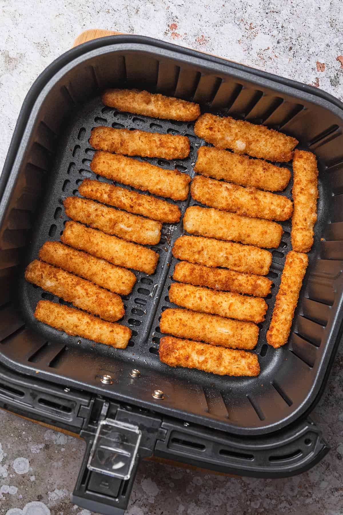 Fish sticks in air fryer basket.