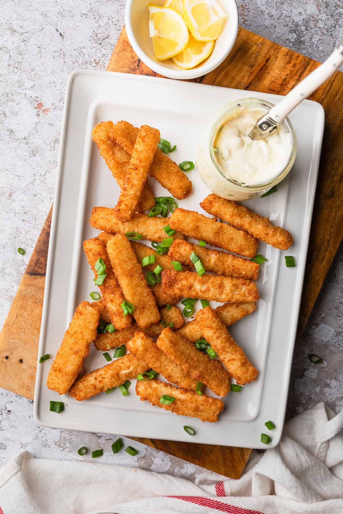 Fish sticks on a platter with lemon and tartar suace.