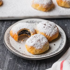 Three air fryer oreos dusted with powdered sugar on a plate.