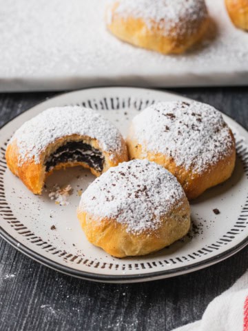 Three air fryer oreos dusted with powdered sugar on a plate.