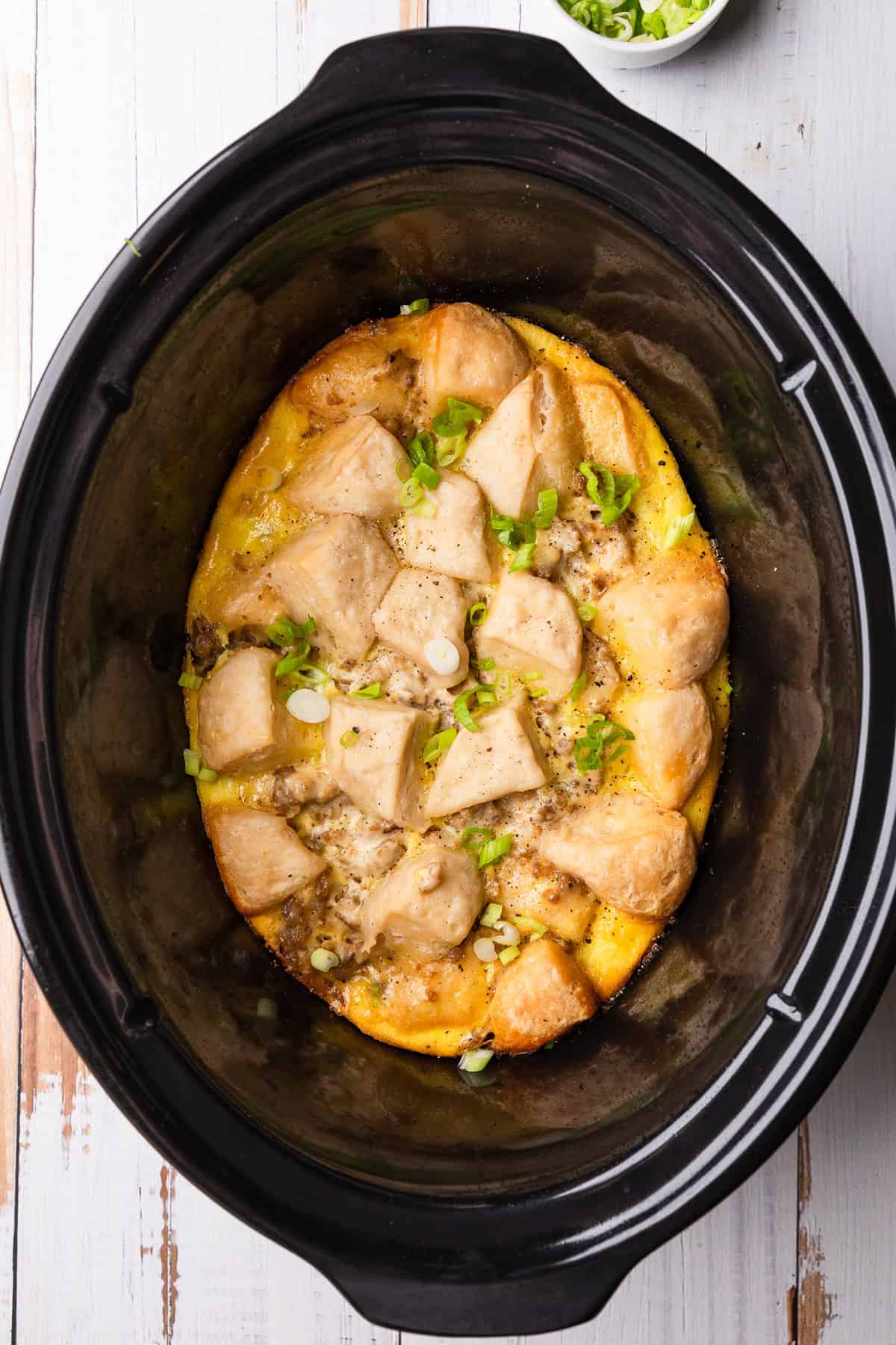 Crockpot of biscuits and gravy casserole with green onions.