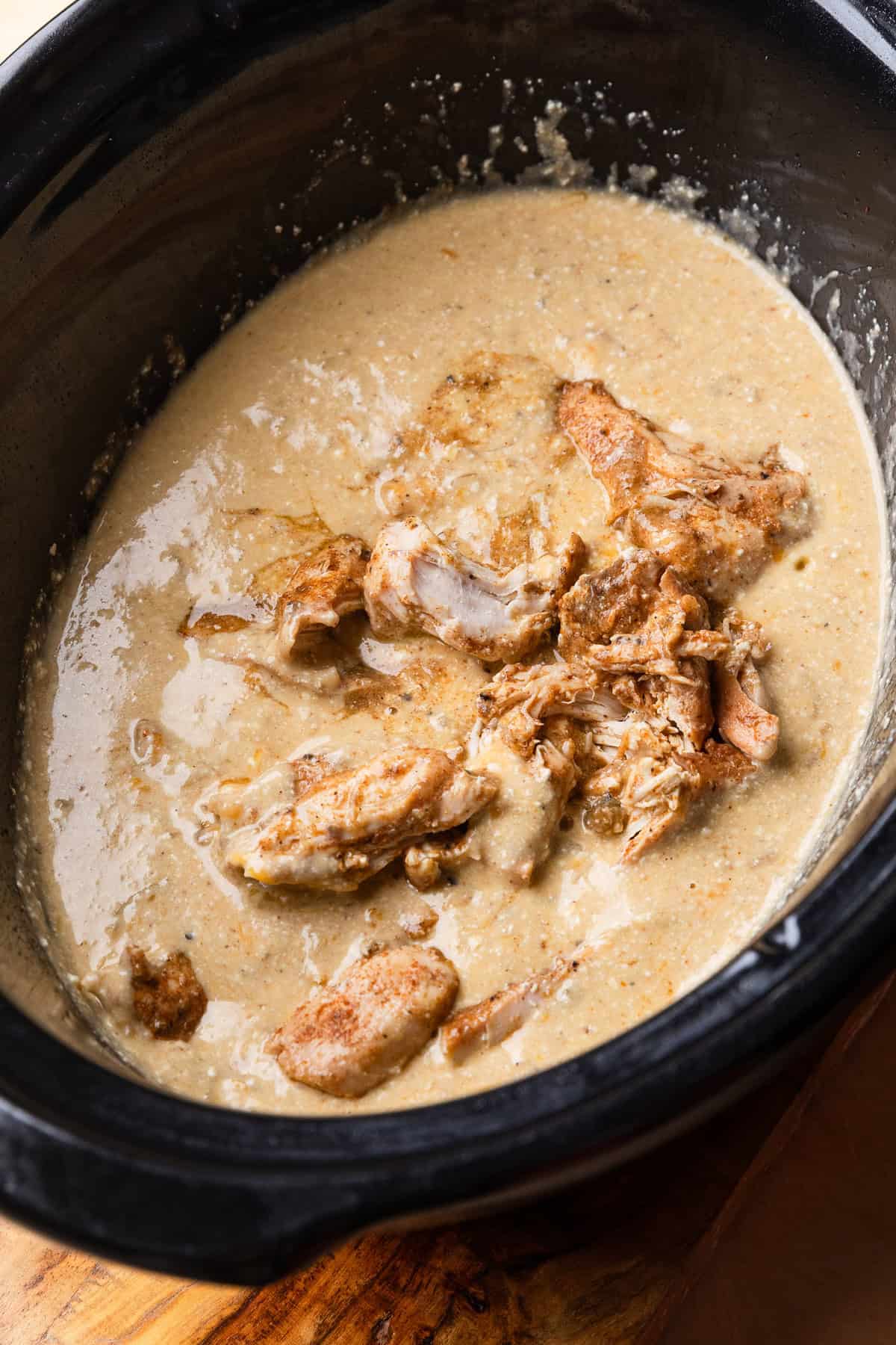 Shredded chicken added to cheese sauce in crockpot.