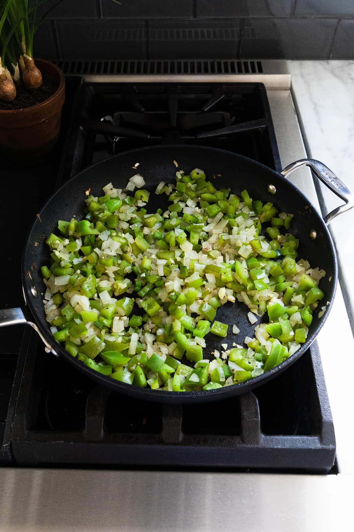 Cooked green peppers, onions, and jalapenos in a skillet.