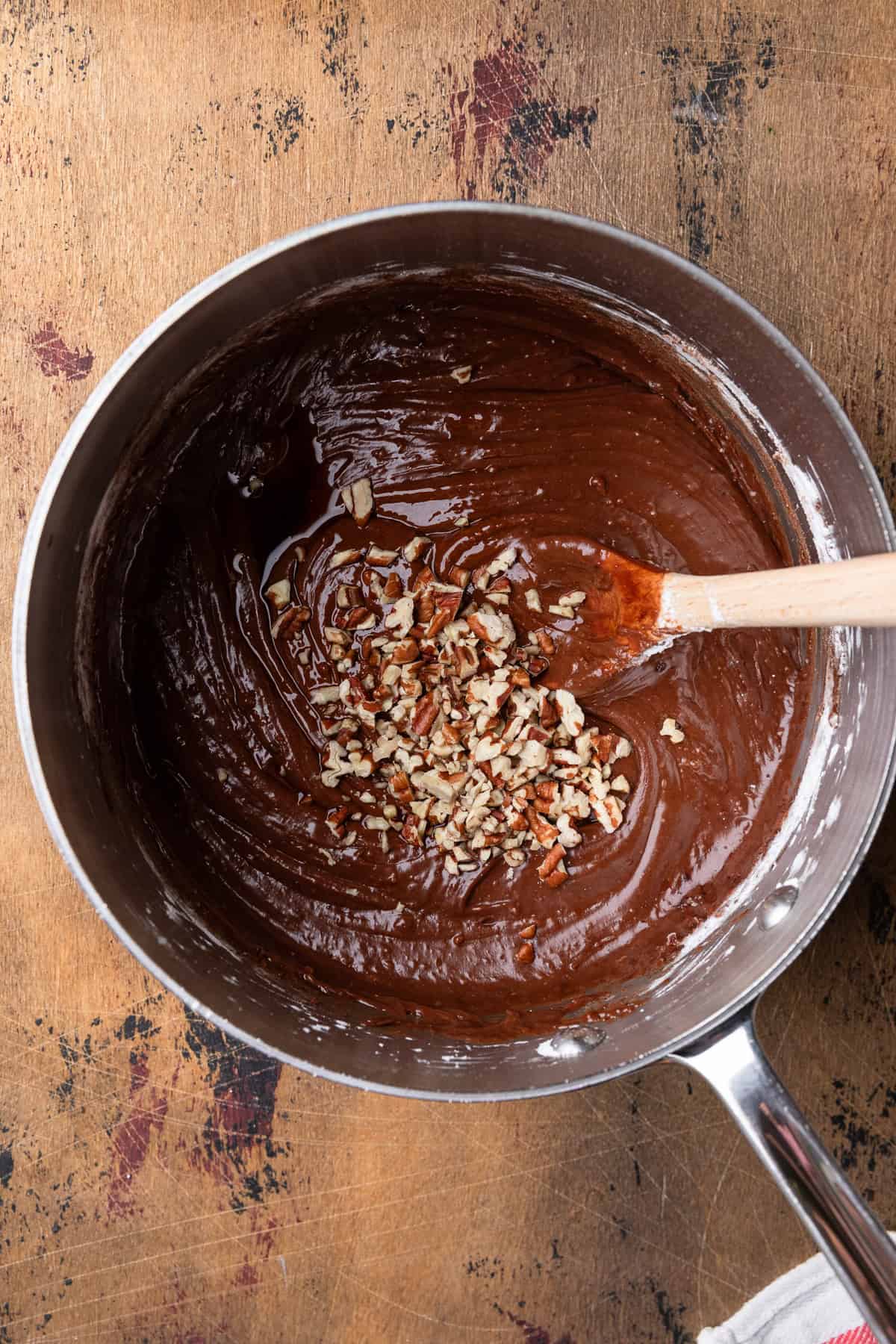 Adding chopped nuts to chocolate frosting.