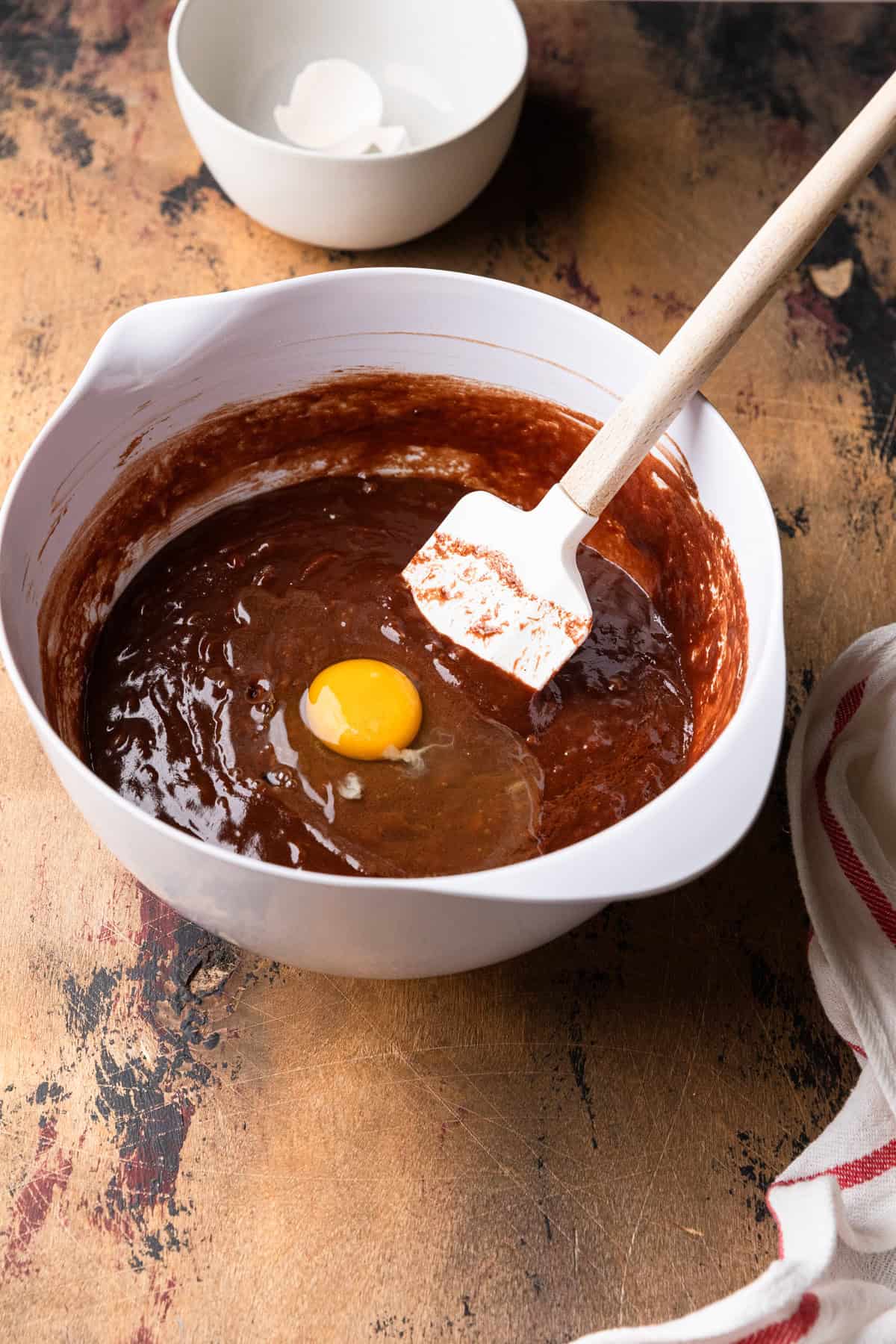 Mixing an egg into chocolate cake batter.