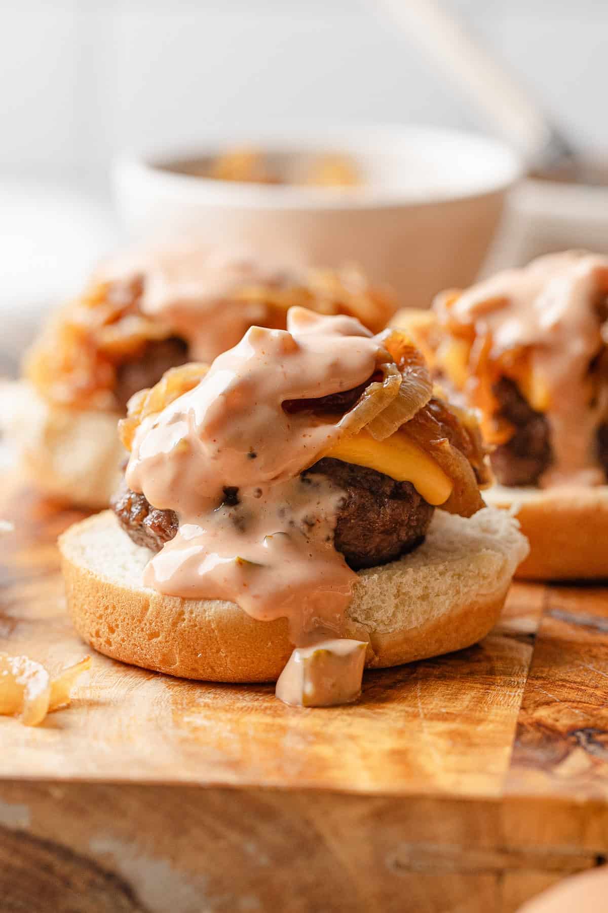 A slider with burger sauce and caramelized onion on a cutting board.