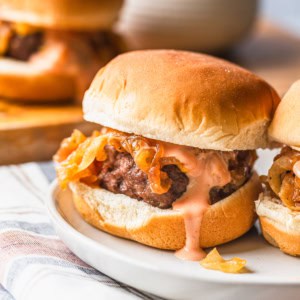 Air fryer slider on a plate with burger sauce dripping over the patty.