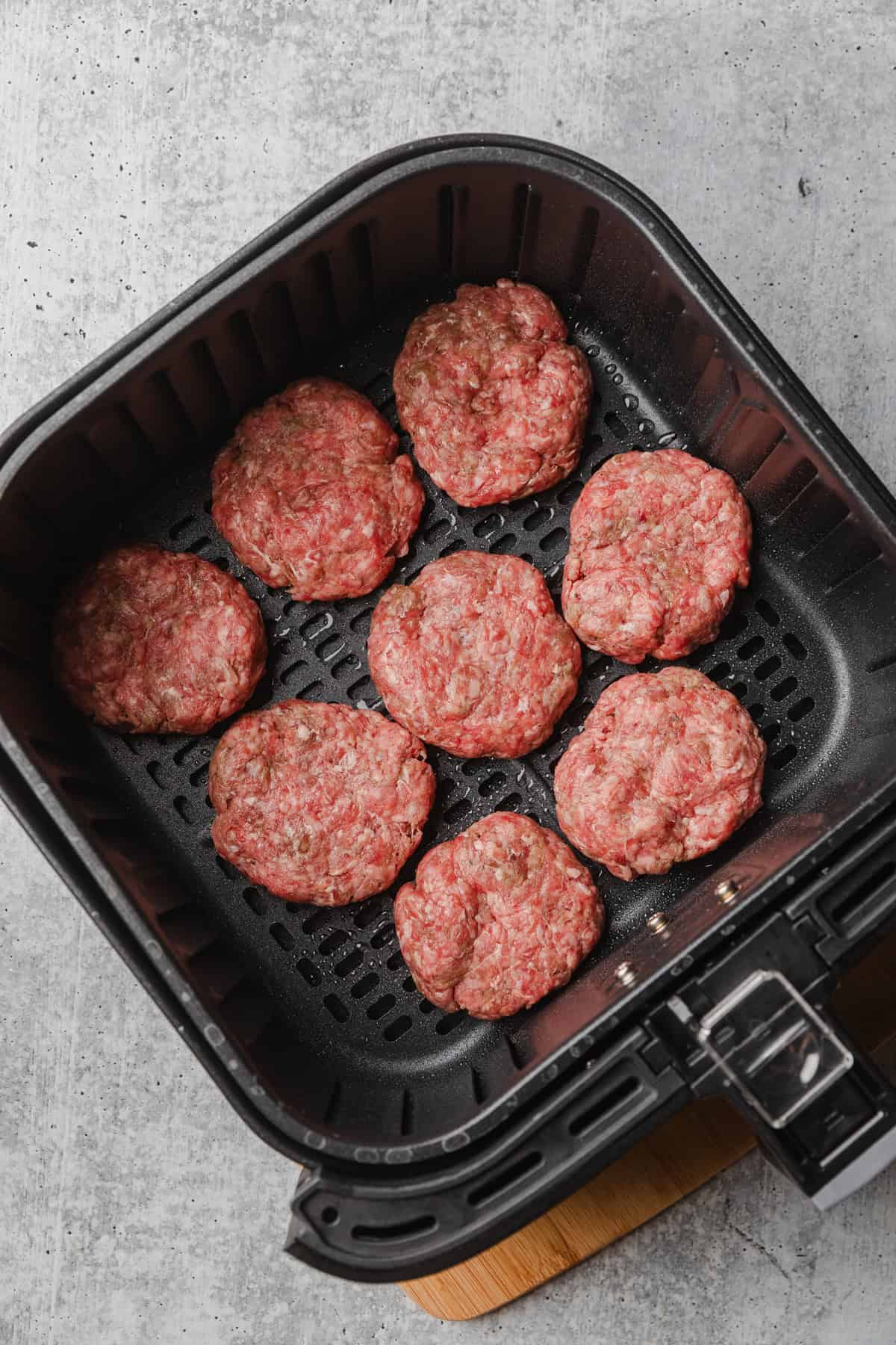 Raw slider patties in air fryer basket.