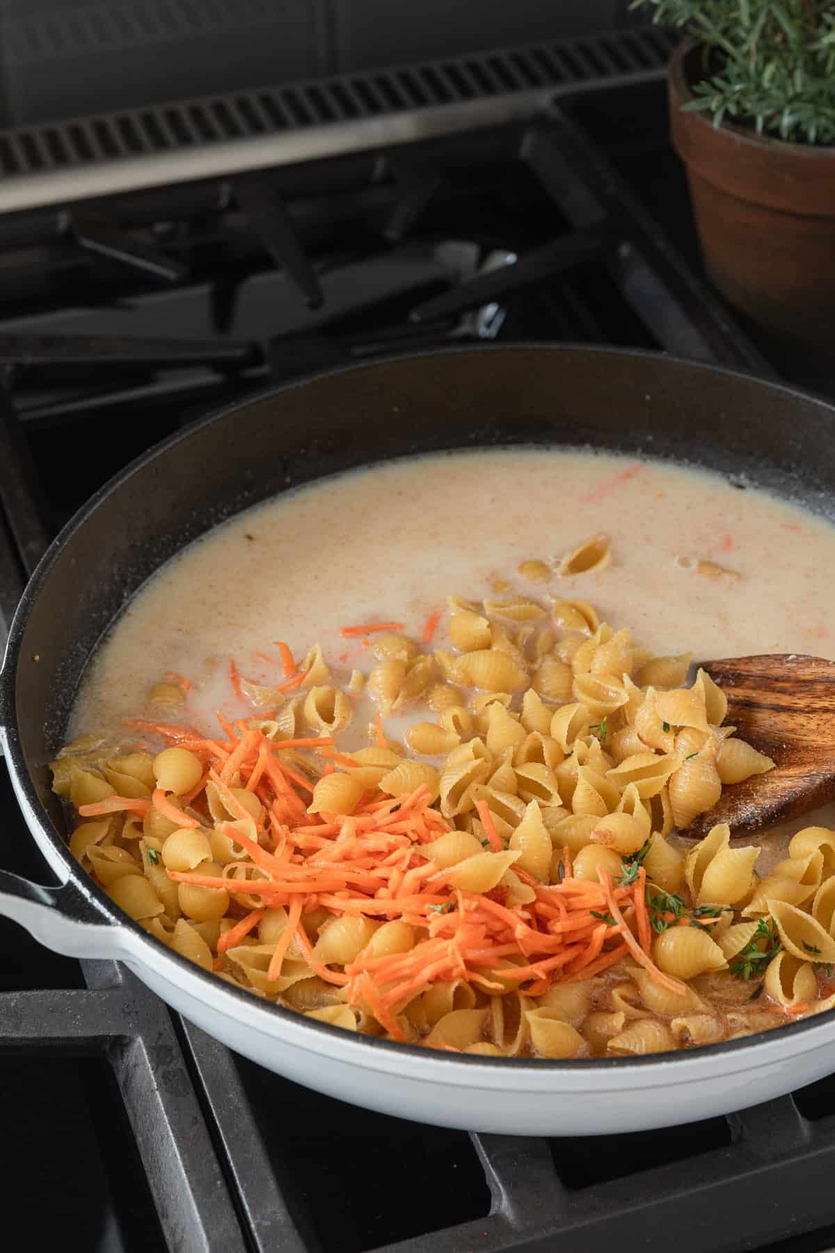 Adding pasta and liquid ingredients to a skillet.