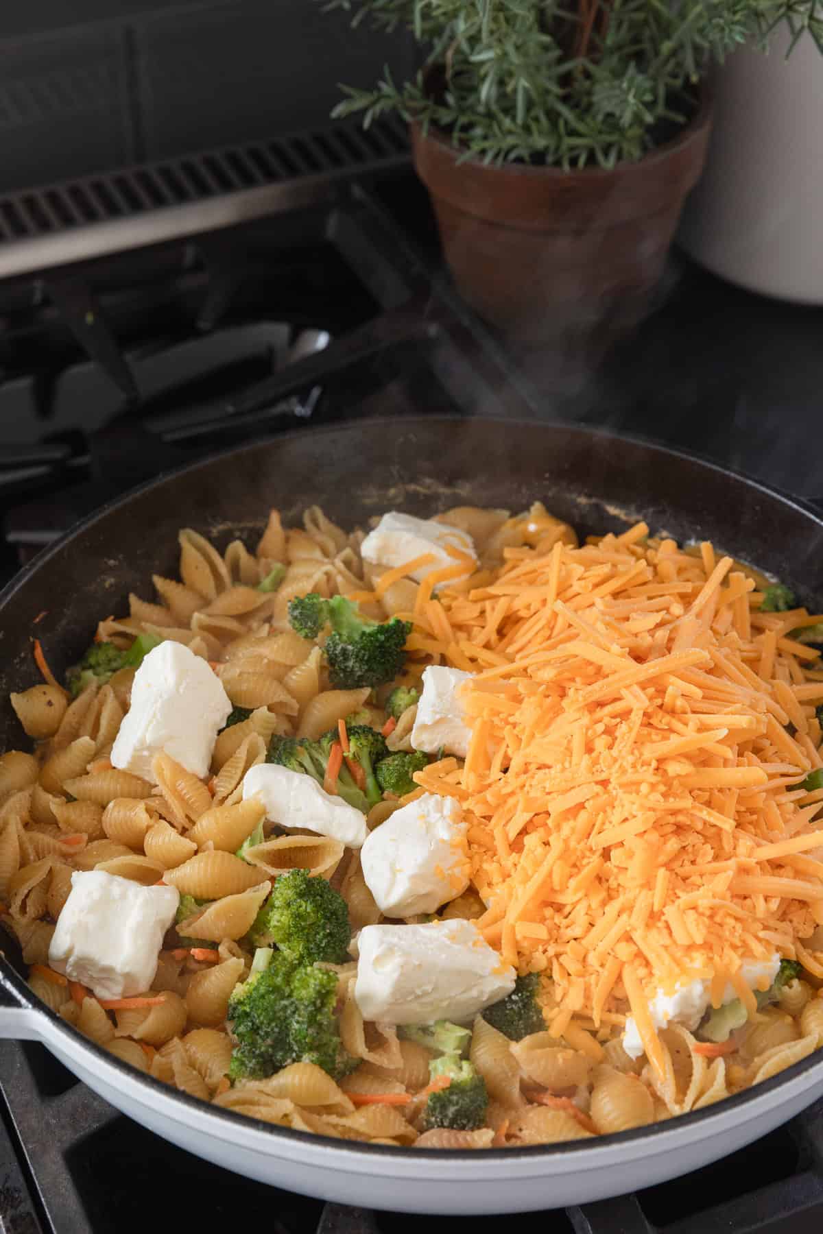 Adding cream cheese and shredded cheese to the skillet.