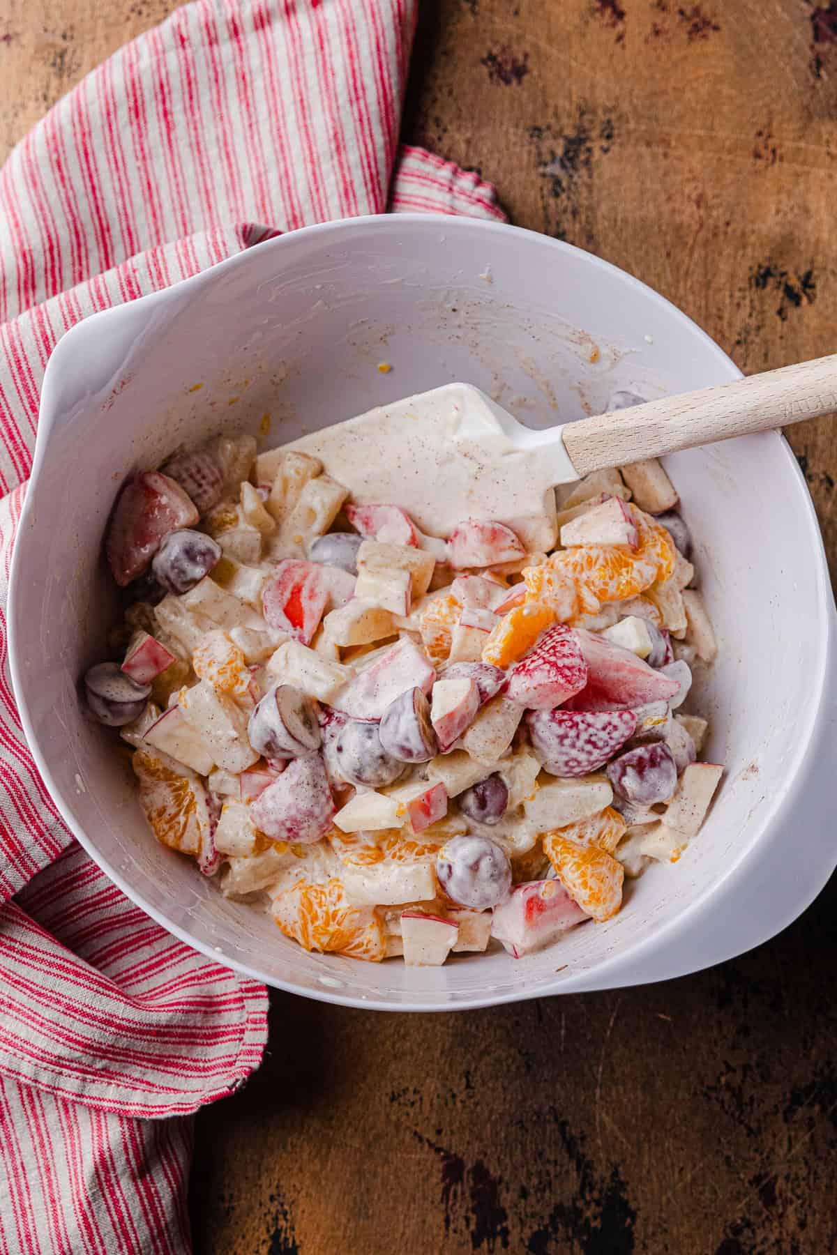 Mixing the cut up fruit the sweetened condensed milk.