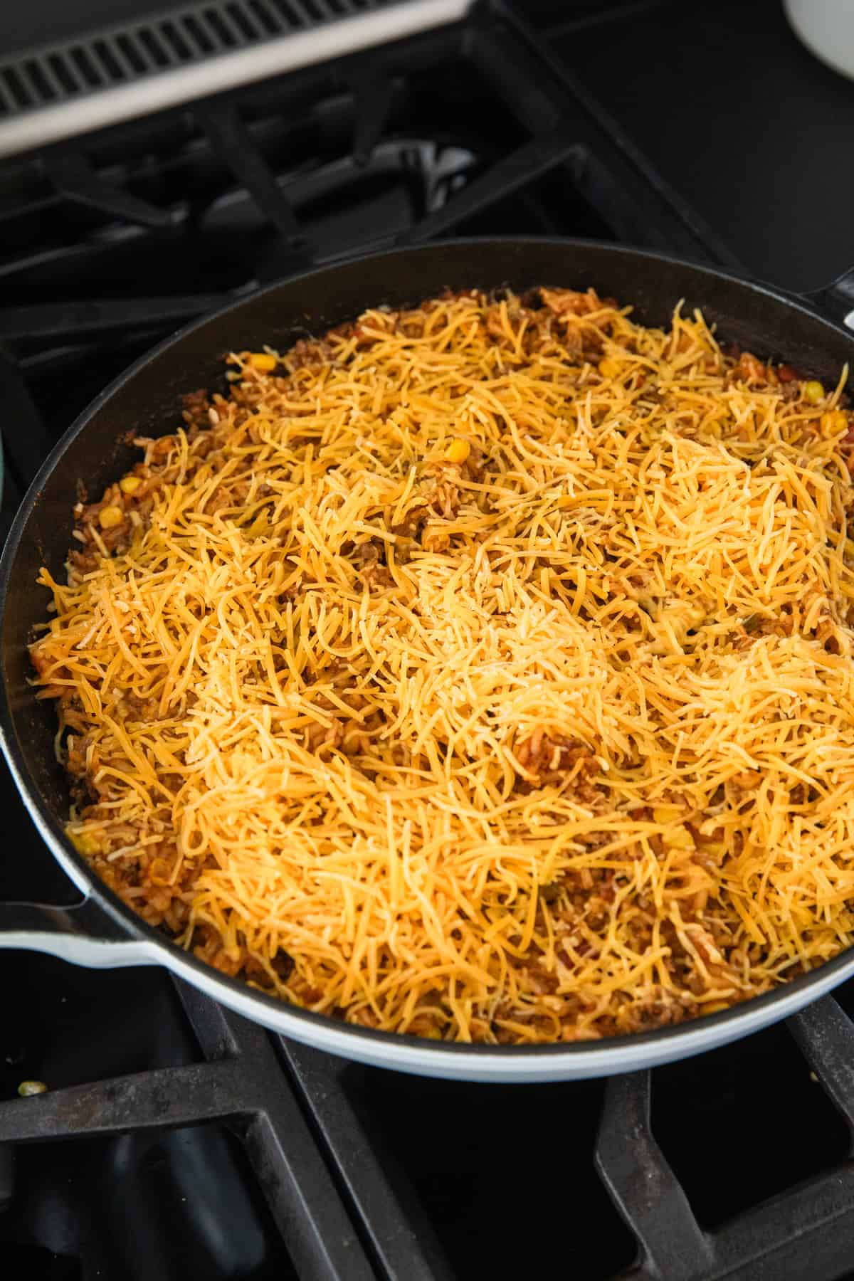 Adding shredded cheese to the cooked rice.