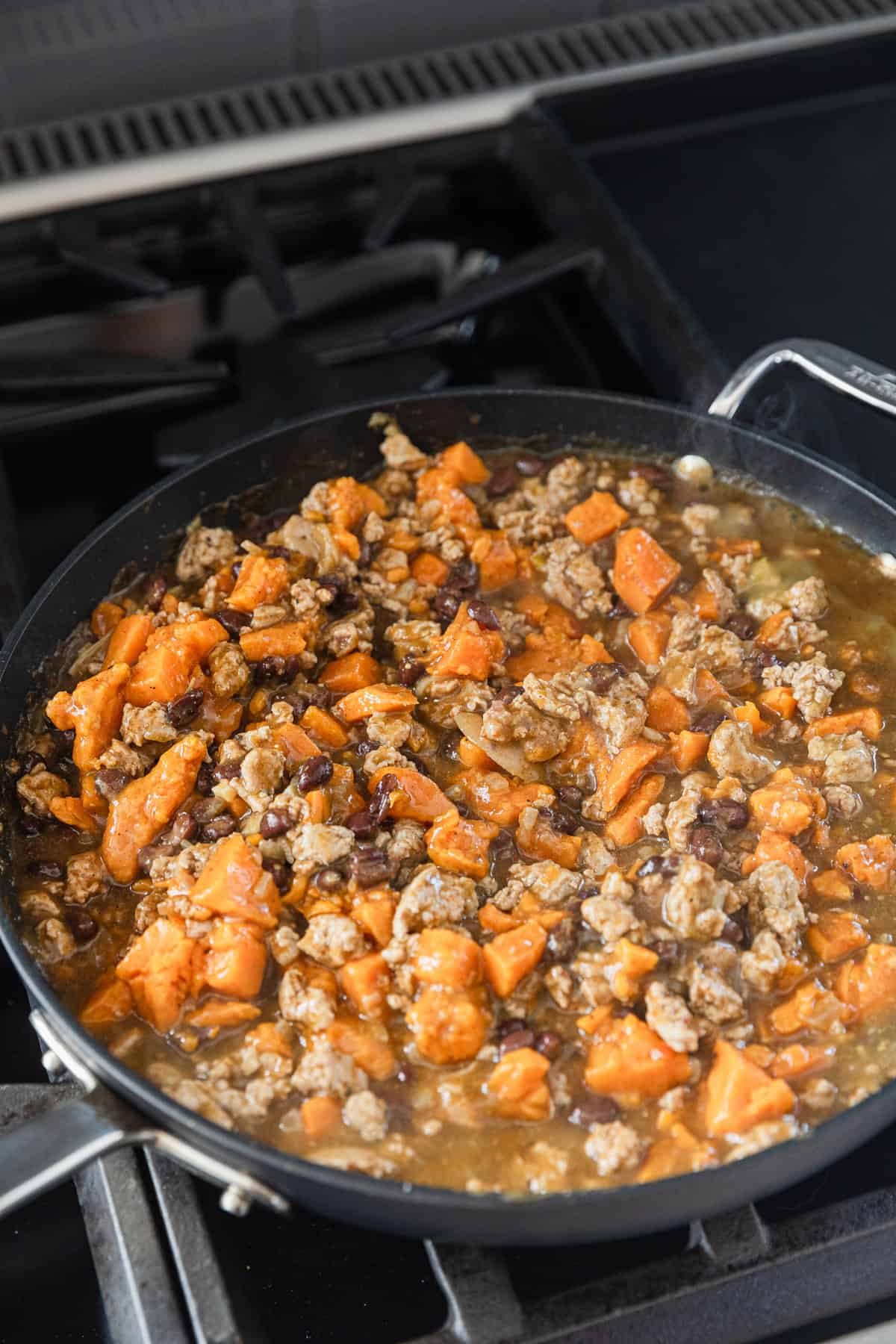 Adding diced sweet potatoes to the skillet.