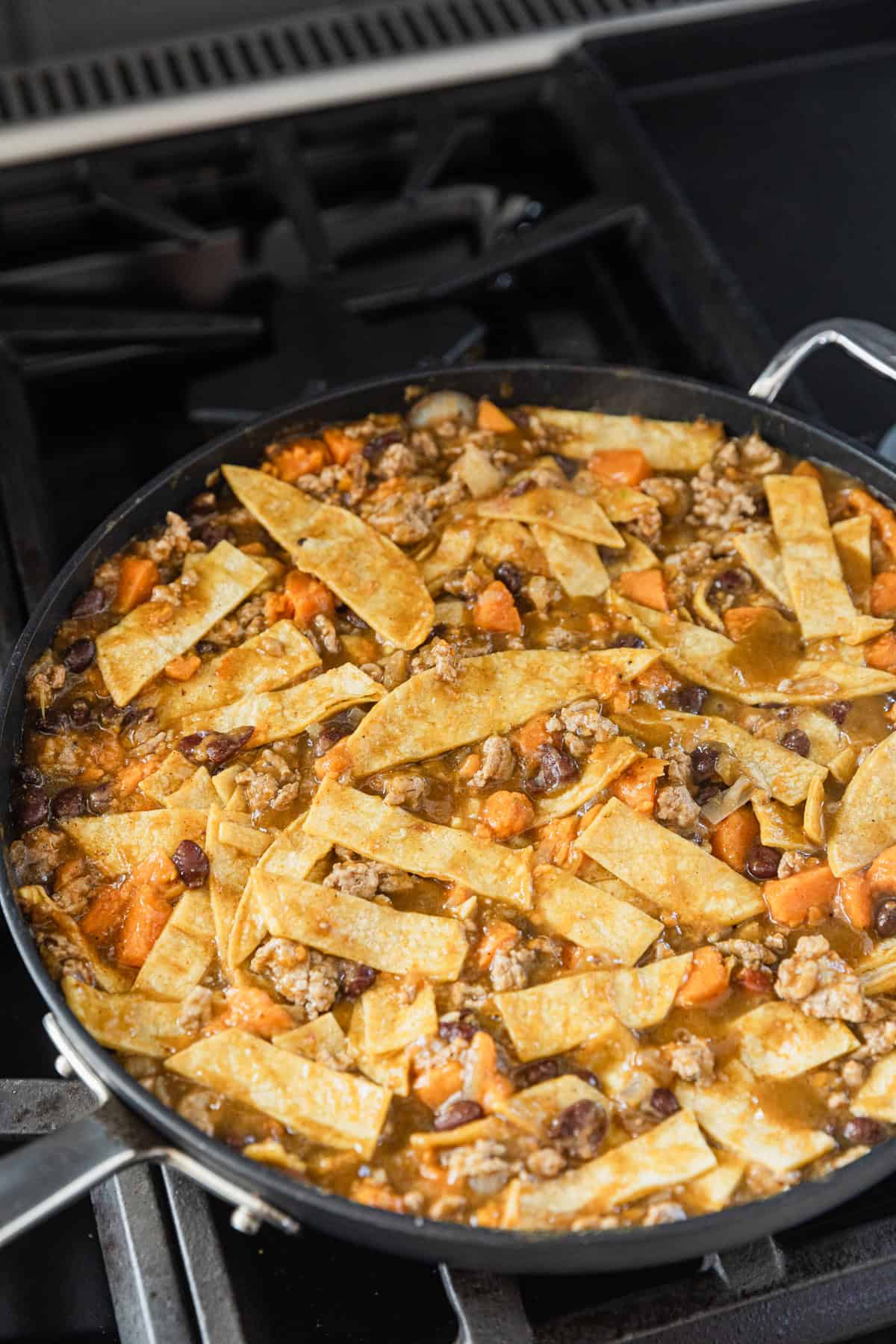 Adding corn tortilla strips to the skillet.