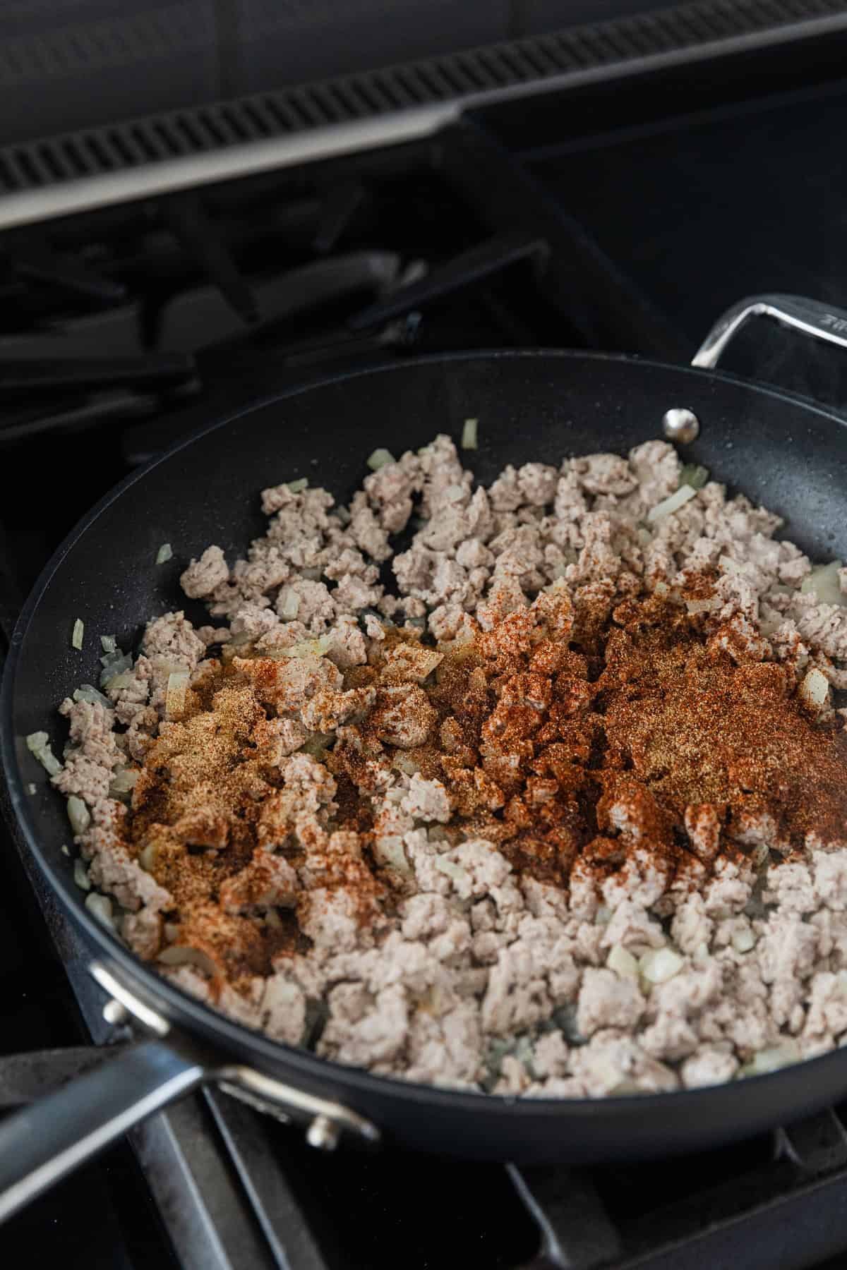 Adding seasoning to cooked meat mixture.