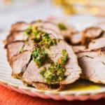 Slices of grilled marinated pork tenderloin with herb sauce.