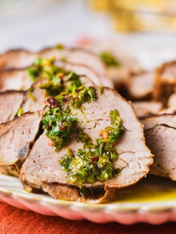 Slices of grilled marinated pork tenderloin with herb sauce.