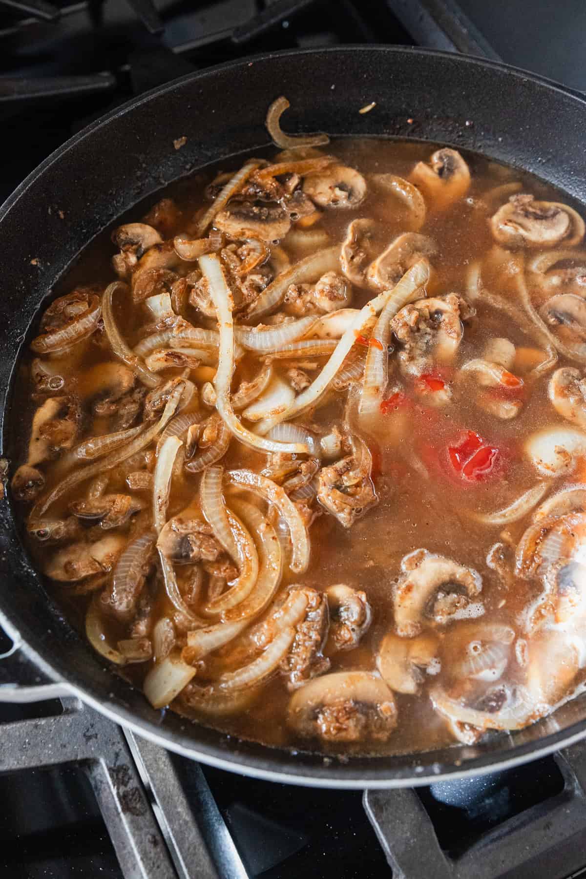 Broth and ketchup added to a skillet to make gravy.