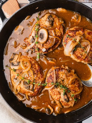 Turkey salisbury steak in a skillet with mushroom gravy.