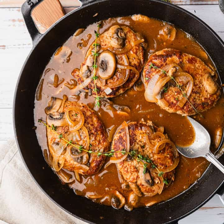 Turkey salisbury steak in a skillet with mushroom gravy.