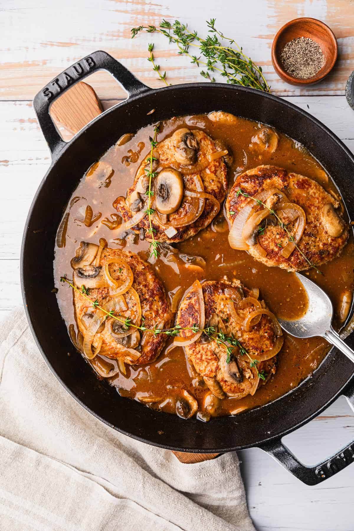 A skillet with turkey patties in a brown gravy.