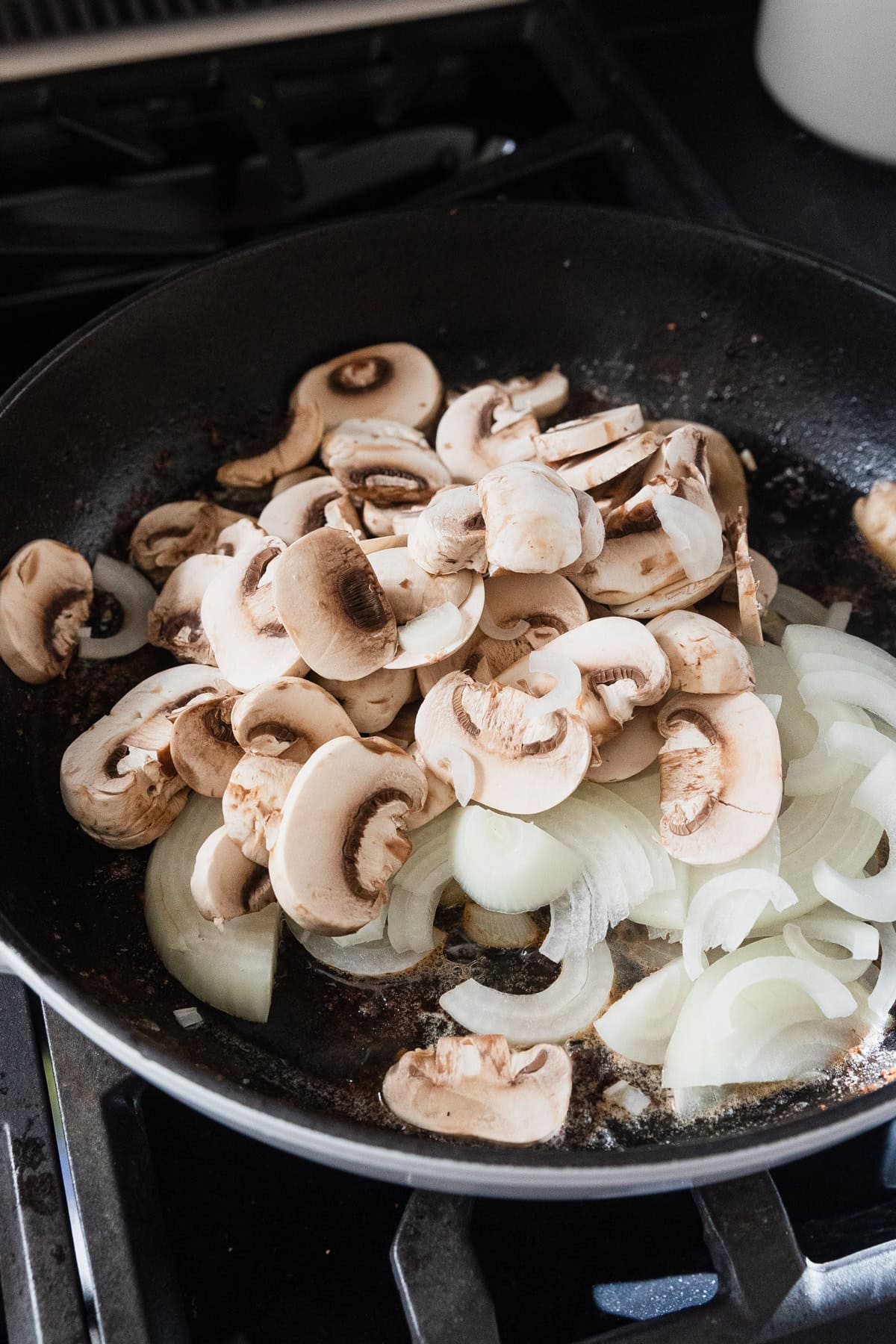 Mushrooms and onions added to a skillet.