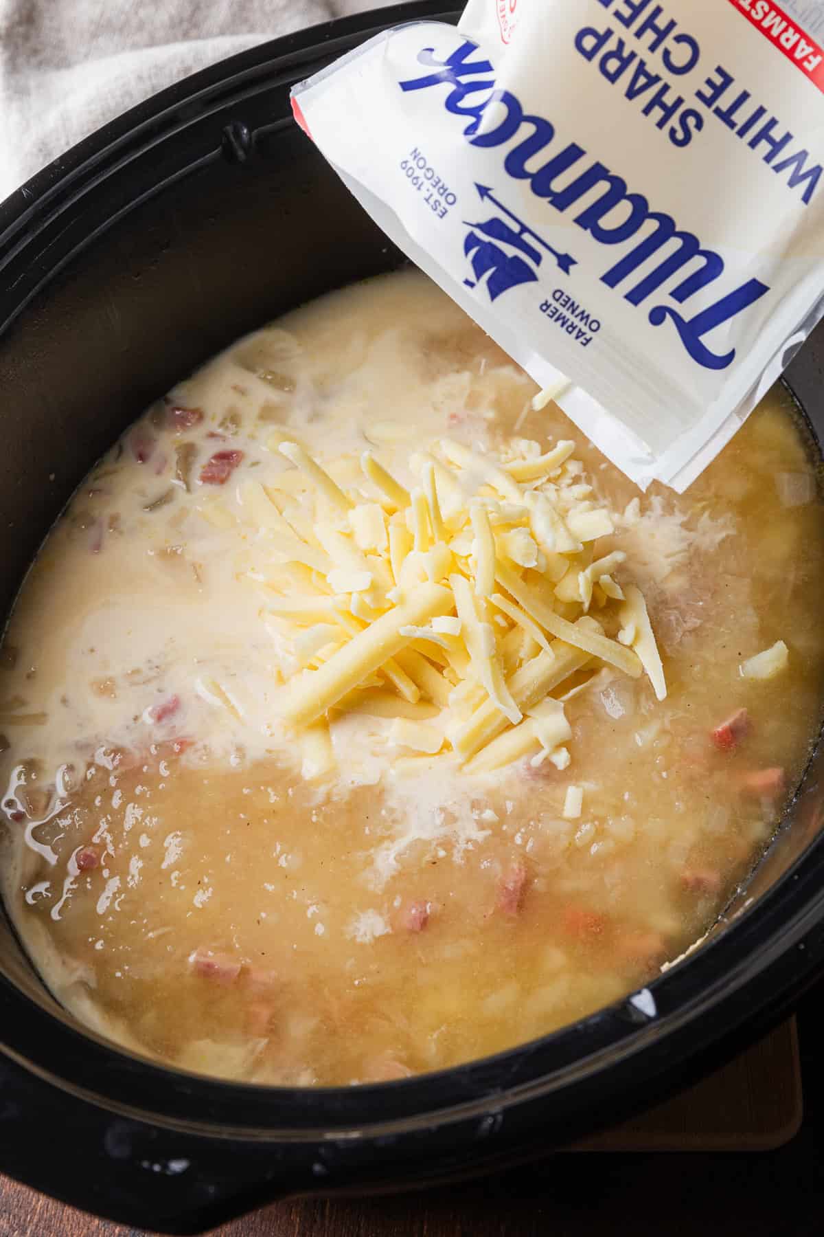 Adding shredded cheese to the soup.