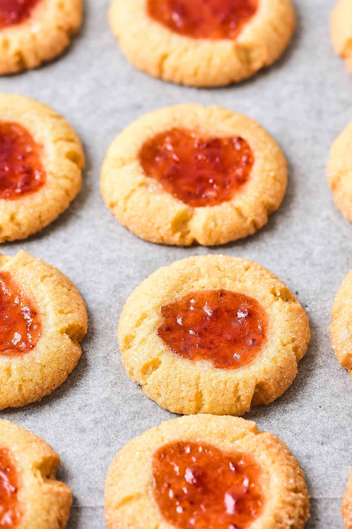 Baked thumbprint cookies on a cookie sheet.