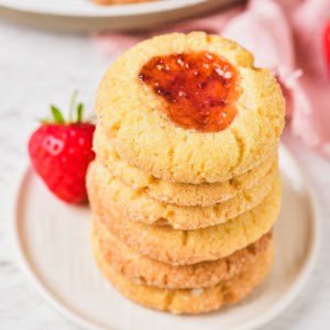 Christmas thumbprint cookie stacked on a plate.