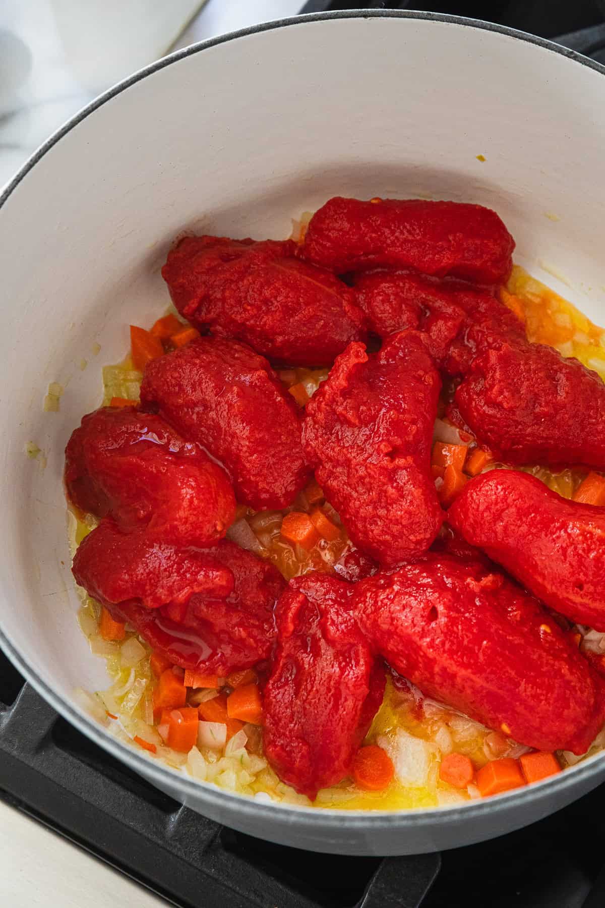 Adding whole san marzano tomatoes to the pot.