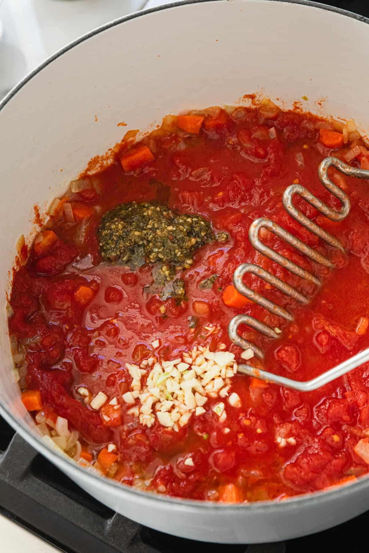 Mashing tomatoes in the soup pot.