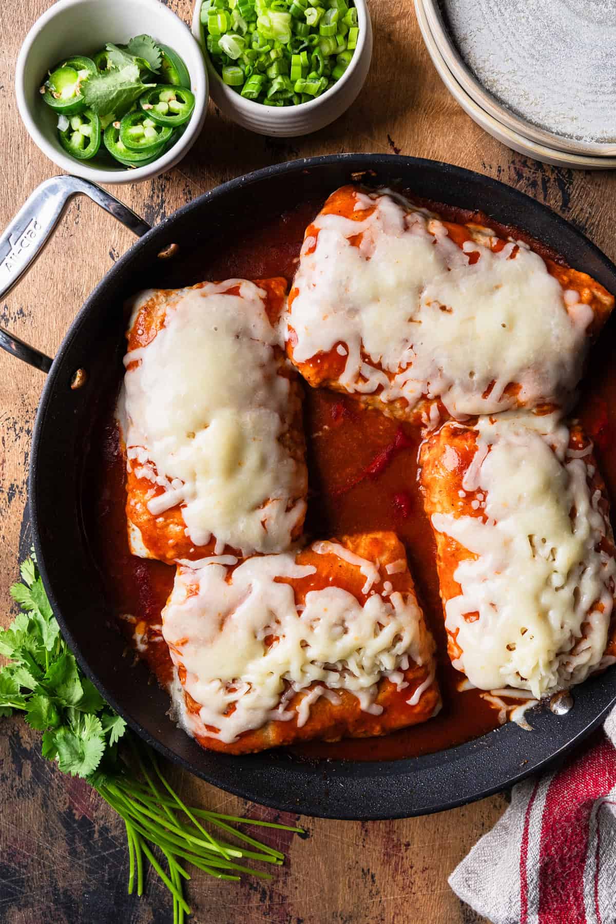 Wet burritos in one pan with melted cheese.