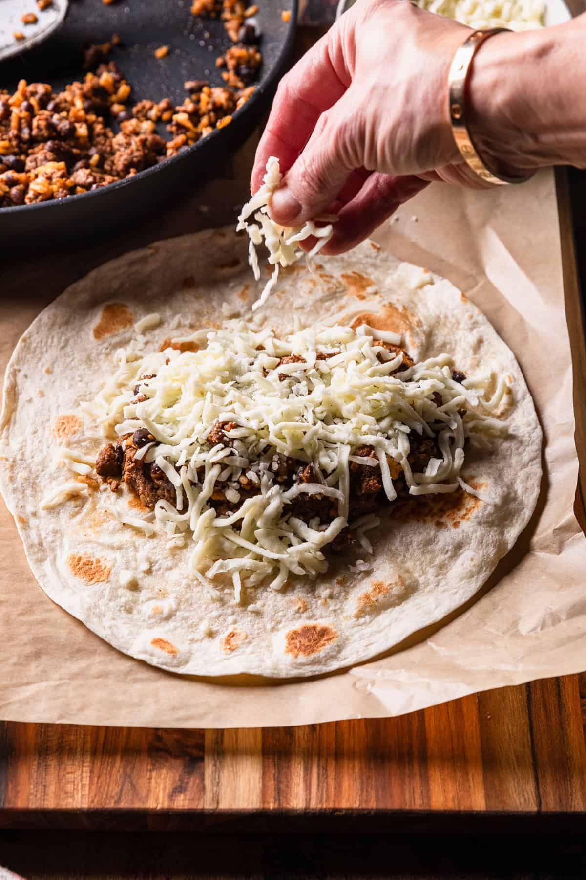 Sprinkling cheese on taco meat.