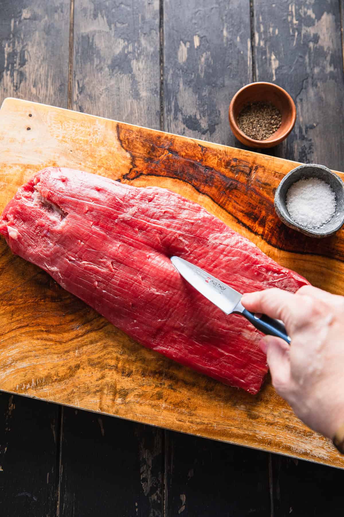 Making small slits in the steak.